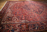 Vintage Heriz carpet with stepped geometric vinery and floral motifs in brick red, navy, and ivory.
