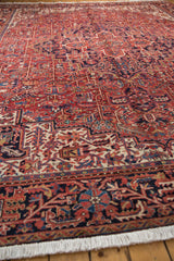 Vintage Heriz carpet end fringe and traditional red and navy geometric border pattern.