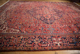 Elaborate geometric vinery and floral motif of the vintage Heriz carpet in pale brick red and navy blue.