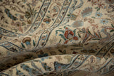 Detailed drawing of birds and trees on the plush, ivory wool pile of a vintage Tabriz carpet.