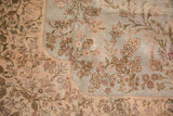 Scalloped corner of a Persian Tabriz rug showing intricate floral sprays on a soft, full pile.