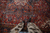 Vintage Heriz carpet's brick red field with sky blue, navy, and orange blossoms and leaves.