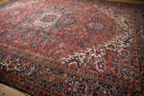Vintage Heriz carpet with dense brick red field and navy border, featuring geometric and floral motifs.