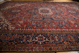 Vintage Heriz carpet's hand-knotted navy border, displaying geometric brick red and orange motifs.