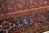 Hand-knotted vintage Heriz rug detail: navy blue geometric border with brick red field.