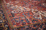 Heriz rug's bold brick red field with geometric blossoms and detailed navy, tangerine border.