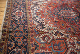 Heriz rug's patterned border and geometric field motifs in rich navy, brick red, and ivory.