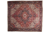 Oversize vintage Heriz square carpet with a bold geometric medallion in brick red, navy blue, and ivory.