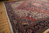 Angled view of the vintage Heriz carpet's dense pile, geometric pattern, and complex navy border.