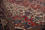Geometric floral motifs and serrated leaves in brick red and navy on a vintage Persian Heriz carpet.