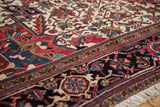 Angled view of the vintage Heriz carpet's plush pile, navy border, and ivory field motifs.