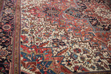 Serrated leaves and geometric floral motifs in brick red and navy on a vintage Heriz carpet.