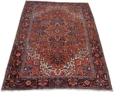 Vintage Persian Heriz rug corner, geometric vinery, brick red field, navy border.