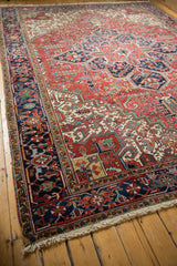 Angled view of the vintage Mehrivan carpet's corner, showing the navy blue border and ivory fringe.