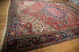 Angled perspective of a vintage Mehrivan carpet's intricate rust red and navy blue geometric field.
