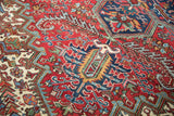 Angled view of the rich, saturated colors in a bursting geometric floral motif on a vintage carpet.