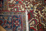 Corner of a vintage Mehrivan carpet folded to show its hand-knotted back and secured fringe.