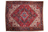 Vintage Persian Heriz carpet with a classic concentric medallion in cherry red, dark navy, and sky blue.