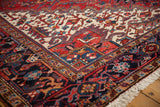 A vintage Heriz carpet's corner with a plush pile, navy border, and detailed geometric patterns.