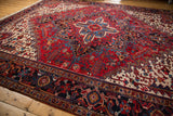 Classic Heriz carpet with geometric medallions in cherry red and navy blue, shown at an angle.