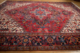 Angled view of a vintage Heriz rug, highlighting its large geometric medallion and dark navy border.