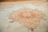 Scrolling tendrils of terra cotta and ivory medallion on a powder blue Tabriz carpet field.