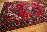 Perspective view of the vintage Mehrivan carpet, showing its plush red pile and navy border.