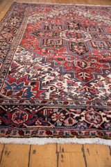 Vintage Mehrivan carpet featuring intricate pinwheel floral motifs in brick red, navy blue, and ivory.