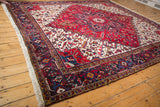 Angled view of the vintage Mehrivan carpet showing its red starburst medallion and traditional navy border.