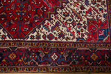 Serrated leaves and vinery in the charcoal and navy blue border of a vintage Mehrivan rug.