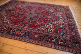 Angled perspective on a vintage Mehrivan carpet highlighting its geometric red field and navy border.