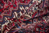 Close-up on the soft, even wool pile of a vintage Mehrivan carpet in cherry red and navy blue.