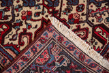 A folded corner reveals the hand-knotted back, intact selvage, and ivory fringe of a Mehrivan rug.