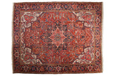 Vintage Persian Heriz carpet with a large geometric medallion on a brick red field with navy blue and ivory details.
