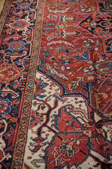 Navy blue Samovar Turtle border alongside the brick-red geometric field of a vintage Heriz carpet.