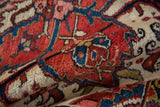 Dense, hand-knotted pile of a vintage Heriz carpet with brick red and navy blue motifs.