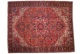 Vintage Persian Heriz carpet with a large geometric medallion, rust-red field, and navy blue accents and border.