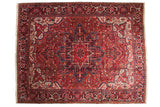 Vintage Persian Heriz carpet with a sharp central medallion in cherry red, sapphire blue, and dusty gold.