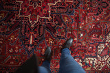 The dense, full pile of a vintage Heriz carpet featuring serrated leaves and vinery in red and navy.
