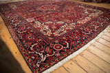 Angled view of a vintage Heriz carpet's corner, showing its full pile and traditional navy border.
