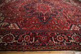 Angled view showing the full, dense pile across the red field and navy border of a vintage Heriz carpet.