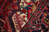 Sharp, geometric contours and serrated leaves in red, navy, and gold on a vintage Heriz carpet.