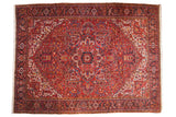 Vintage Heriz carpet with an oversize geometric medallion in brick red, navy blue, and ivory.