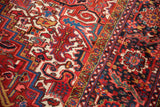 Contoured serrated leaves and floral arabesques in red, navy, and ivory on a vintage Heriz carpet.