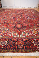 Vintage Heriz carpet from a low angle, showing the navy border and receding red geometric field.