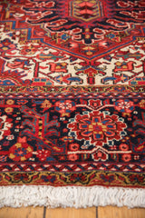 Close view of the vintage Heriz carpet's plush pile, navy floral border, and ivory fringe.