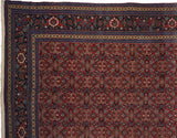 Corner of a vintage Tabriz carpet showing the wide, reciprocating turtle motif border.