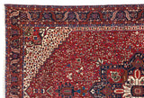 The intricate serrated leaf main border and geometric corner design of a vintage Karaja Persian carpet.