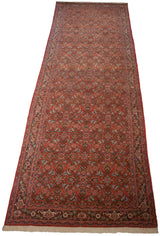 Long vintage Persian Tabriz runner viewed from an angle, showing its complex Herati design.