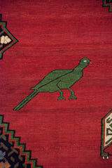 A pictorial mallard green bird on the abrashed red field of an antique Karabagh collector rug.